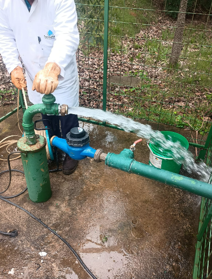 Técnico da Consultech testando a vazão de um poço com água jorrando